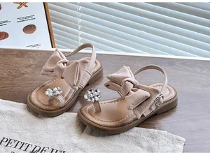 Close-up of girls' pink sandals featuring a large bow and sparkling flower rhinestones.