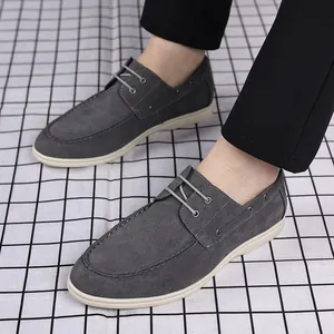 Side view detail of grey suede men's loafers with white soles and laces