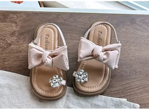 Detailed view of girls' pink sandals featuring an oversized bow and rhinestone flower ornament