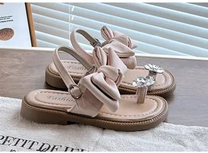 Close-up of pink girls' bow sandals with sparkly rhinestone flowers and buckle straps