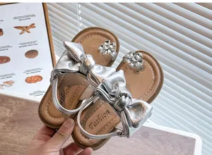 Detail view of silver girl's sandals with metallic bows and rhinestone flower accents.