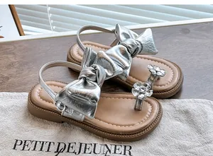 Close-up detail of girls' silver bow sandals with elegant rhinestone flower decor