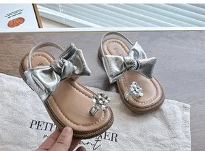 Close-up detail of silver girls princess sandals with large bow and rhinestone flower ornament