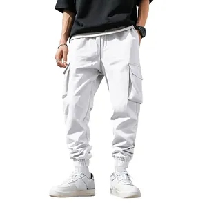 Dettaglio dei pantaloni cargo bianchi da uomo con design multitasche e polsini stile jogger