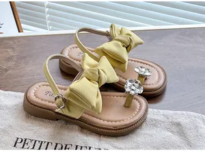 Detail view showing the large fabric bow and rhinestone flower on yellow girls' sandals