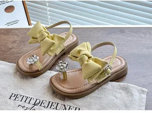 Close-up of yellow girl's sandals with large leather bow and sparkling rhinestone flower