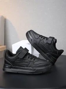 Detailed view of children's all-black athletic sneakers with adjustable velcro closure.