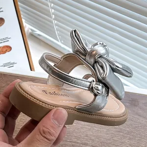 Silver metallic girls sandals with a large bow detail and adjustable ankle strap