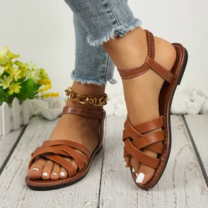 Detailed view of fashionable brown flat Roman sandals with cross-strap design for women