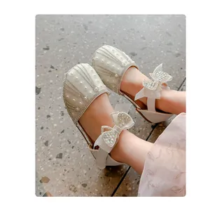 Detailed shot of white princess shoes for girls with rhinestones and pearl bows