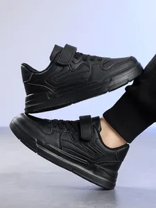 Macro view of black children's athletic shoes featuring durable velcro straps and texture.
