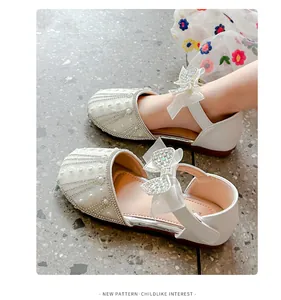 Detailed view of white girls' princess sandals decorated with rhinestones and bows