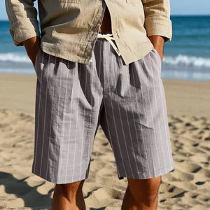 Men's relaxed vertical striped linen beach shorts with drawstring waist in a beach setting.