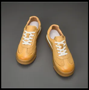 Detail of tan men's leather sneakers with breathable perforations and white laces