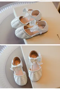 Detailed close-up of elegant white girls' princess shoes with rhinestone bowknots