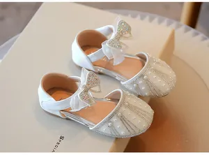 Close-up detail of white girls' princess shoes featuring shimmering rhinestones and a bow