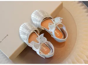 Close-up of white girls' princess shoes with pearl and rhinestone bowknot detail