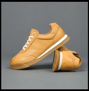 Side detail of premium tan leather sneakers with gum sole and white laces.