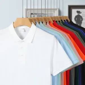 Surtido de polos multicolores de algodón para hombre colgados en perchas de madera.