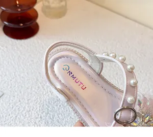Detailansicht von rosa Mädchensandalen mit Perlenriemen und funkelnden Strasssteinen.