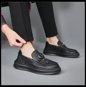 Detailed shot of men's black perforated leather loafers with buckle on model's feet