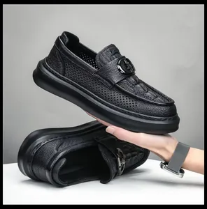 Macro view of black perforated leather men's loafers featuring a thick rubber sole