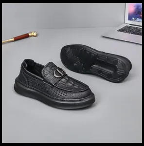 Macro view of black perforated genuine leather loafers with stylish metal buckle and sole detail