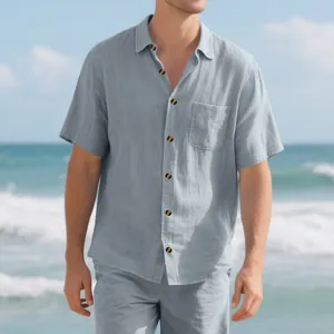 Detail view of men's loose fit light blue linen short sleeve shirt set on a beach scene.