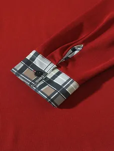 Nahaufnahme der roten Polo-Manschette mit klassischem Karomuster und schwarzem Knopf-Detail