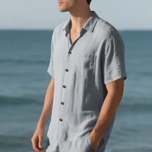 Detail of a man wearing a light blue casual short-sleeve button-up shirt on the beach.