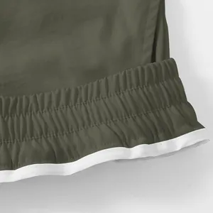 Primo piano della vita elastica di pantaloni cargo outdoor verde oliva con profilo bianco.