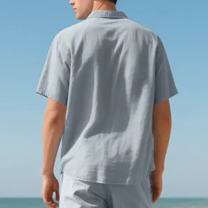 Back view of a men's light grey short-sleeved woven shirt in a summer beach setting