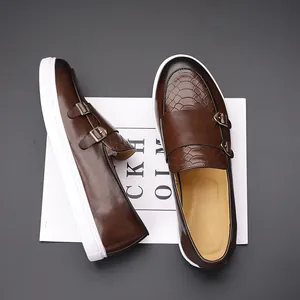 Vue détaillée de mocassins en cuir marron à texture croco, boucle monk strap et semelle blanche.