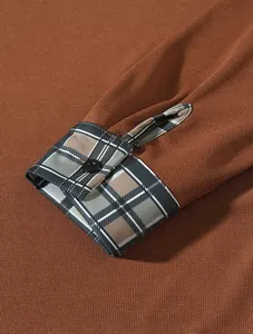 Detailaufnahme eines braunen Herren-Poloshirts mit karierter Manschette und Knopf