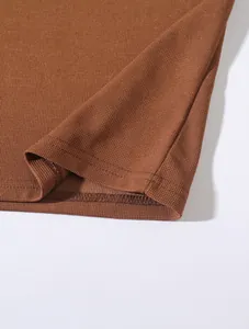 Detaillierte Nahaufnahme eines braunen Waffelstrick-Poloshirts mit Saumnaht und Textur