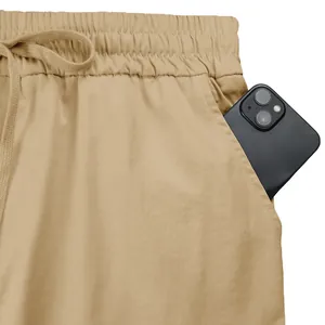 Dettaglio macro della tasca profonda dei pantaloni cargo kaki con uno smartphone