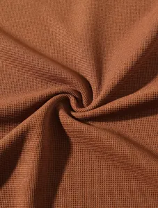 Nahaufnahme des atmungsaktiven braunen Waffelstrickstoffs für ein Herren-Poloshirt.