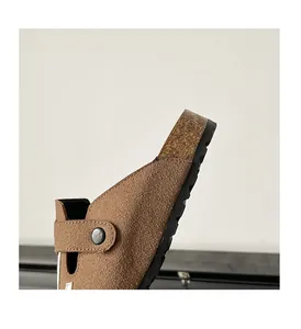 Close-up detail of a brown suede Boston style clog shoe with metal rivet and cork sole