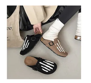 Close-up detail of stylish women's clogs with a unique white skeleton hand bone design.
