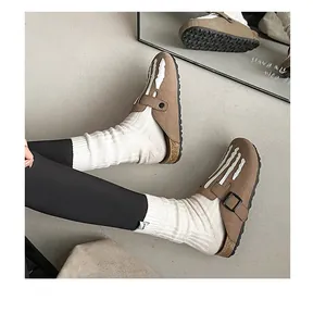 Detail of brown suede clogs with white skeletal hand design and cork platform sole
