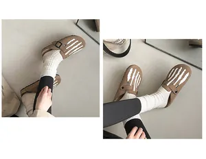 Close-up detail of women's brown suede clogs featuring white skeleton hand pattern.