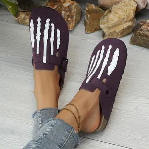Close-up detail of purple suede clogs with white skeleton hand patterns and cork soles