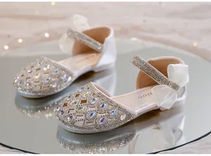 Dettaglio macro delle scarpe da principessa bianche per bambine con strass luccicanti.