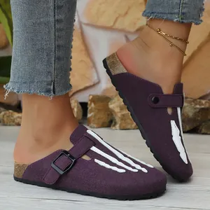 Detailed view of purple suede clogs featuring white bone pattern and cork midsole.
