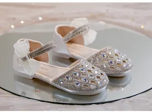 Dettaglio di scarpe da principessa bianche con strass per bambine e fiocco in organza