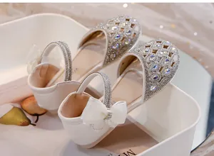 Vista ravvicinata delle scarpe da principessa bianche per bambine con strass e fiocco.