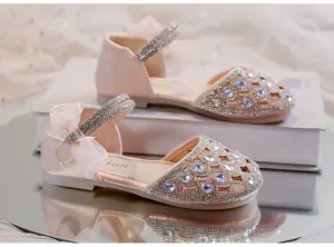 Dettaglio dei sandali da principessa rosa per bambine con strass scintillanti e fiocco.