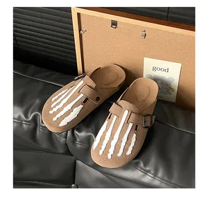 Detailed view of brown suede mules featuring a unique white skeleton hand bone design