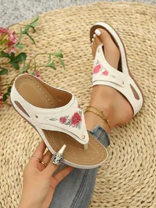 Close-up view of elegant floral embroidery on off-white platform flip-flops for women