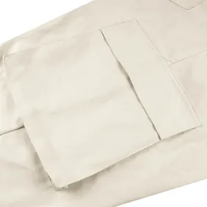 Vista macro dettagliata delle cuciture e della trama di una tasca con patta di pantaloni cargo beige